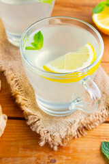 Ginger tea with lemon on a burlap napkin. Two cups of ginger tea with mint on wooden background. Top view