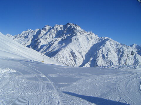 Top of a ski piste in France, with snow flattened and blue sky.