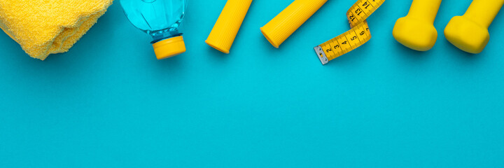 Flat lay photo of fitness equipment over turquoise blue backgound. Top view of yellow street workout objects. Yellow fitness objects on the blue background with some copy space