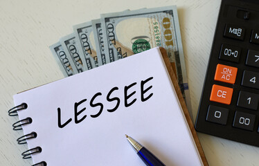 LESSEE word in a notebook with a pen against the background of dollar bills