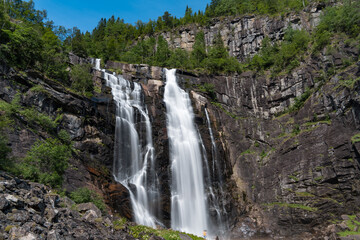 Obraz premium Skjervsfossen waterfall, on the road between Granvin and Voss, Hordaland, Norway. Impressive beautiful win falls plunging 150 metres in a narrow canyon