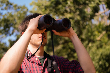 Man in plaid short look through binoculars. Forest hiking. Bird watching. Searching for opportunities concept. Adventure quest 