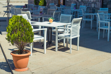 white tables and chairs of a street european cafe on a sunny day