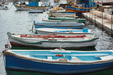 Fototapeta na wymiar old fisherman village and important tourist attraction on the island. Traditional eyed colorful boats Luzzu in the Harbor of Mediterranean fishing village Marsaxlokk