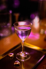 A lifestyle atmospheric photo of a cocktail in a nick and nora glass at the bar in the evening, high iso, selective focus