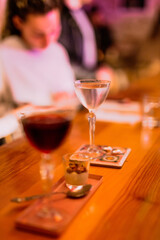 A lifestyle atmospheric photo of a cocktail in a nick and nora glass at the bar in the evening, people in the background, high iso, selective focus