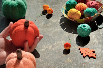 Hand with decorative felt pumpkin, Yarn balls, more pumpkins, Fall berries and leaf. Creative...