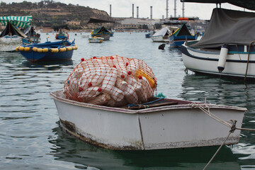 Small fishing boat with plastic bottles. Traditional maltese fishing boat in Marsaxlokk Malta.