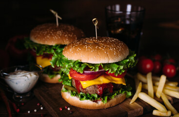 Two home made fresh tasty burgers with lettuce and cheese on wooden table.