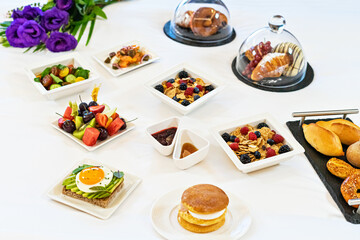 Tray plates with assorted breakfast meal on a bed in a hotel room
