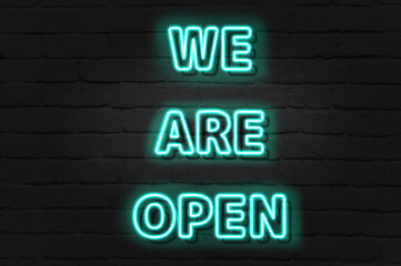 WE ARE OPEN - green neon light entrance sign on brick wall