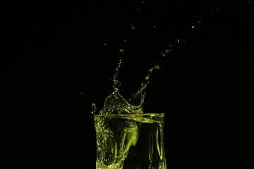 splash of water in a glass by ice cube on black background