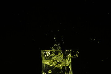 splash of water in a glass by ice cube on black background