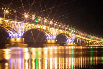 Fototapeta na wymiar The bridge across the river glows at night