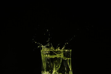 splash of water in a glass by ice cube on black background