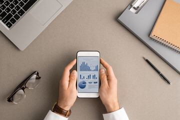 Flat layout of hands of young modern economist or accountant analyzing data
