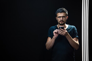 Portrait of a man on a black background with a phone in his hands