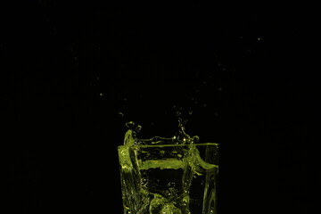 splash of water in a glass by ice cube on black background