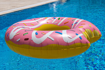 pink inflatable donut doughnut floating mattress in swimming pool. Beach pool accessories. Summer...