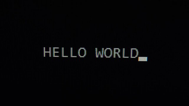Typing hello world text on black screen close up 4k footage. Typing The Classical Programmers' Greeting Message.