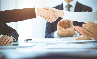 Business people shaking hands finishing up meeting or negotiation in sunny office. Business handshake and partnership concepts