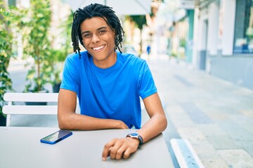 Young african american man smiling happy using smartphone sitting on the table at terrace.