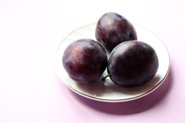 Fresh plums on a platter, close-up, side view, space for text