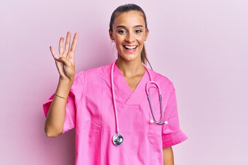 Young hispanic woman wearing doctor uniform and stethoscope showing and pointing up with fingers...
