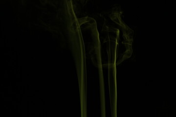 yellow smoke from incense on a black background