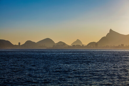 Beautiful distant view of Corcovado mount and a mountains chain at sunset with blue sky; Picture taken from Niteroi, Rio de Janeiro, Brazil. Detail of the sea. Copy space for text.