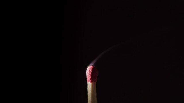 Close up of an isolated Match stick catching fire from start to finish against a black background.