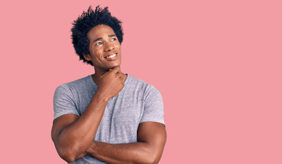 Fototapeta na wymiar Handsome african american man with afro hair wearing casual clothes with hand on chin thinking about question, pensive expression. smiling with thoughtful face. doubt concept.