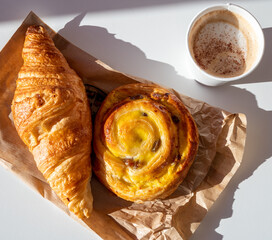 French breakfast in bakery served outdoor, cups of coffee and fresh baked croissants and pastry, morning food