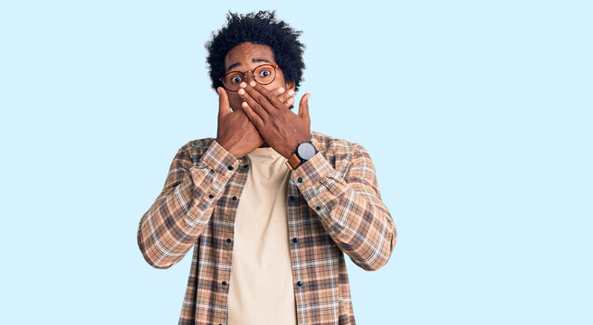 Handsome african american man with afro hair wearing casual clothes and glasses shocked covering mouth with hands for mistake. secret concept.