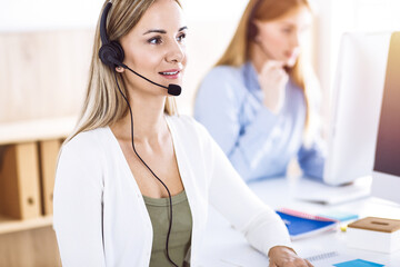 Toned portrait of call center operator at work. Group of people in a headset ready to help customers. Business concept