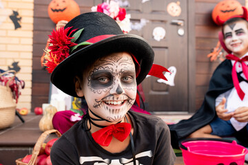 Happy cute boy with painted face sitting in front of camera against his friends