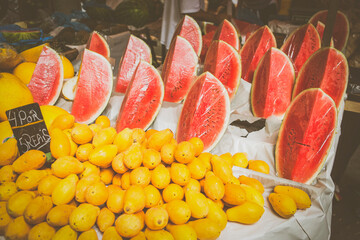 Fresh fruits in exposition on a table at the public free fair of Jardim Botânico at Rio de Janeiro, Brazil. Lots of yellow papayas and sliced watermelons exposing its red inner part.