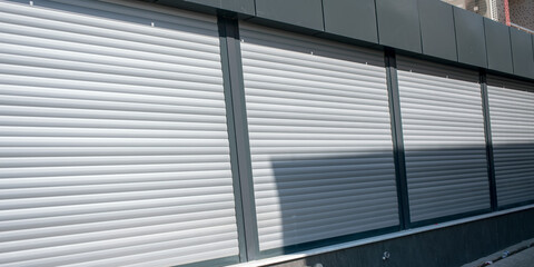 wall of store with closed gray shutters outdoors