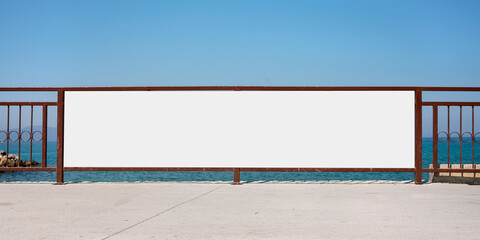 long advertising white blank banner with mockup place for commercial information hangs on fence sea background