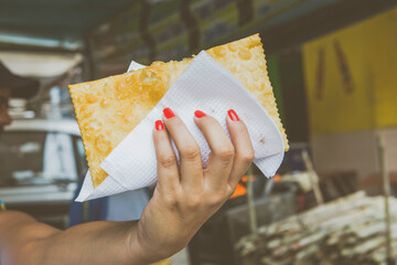 Female hand holding pastel at the free fair of Jardim Botânico, Rio de Janeiro, Brazil. Street food reinventing oneself new normal job during and after covid 19 pandemic concept.