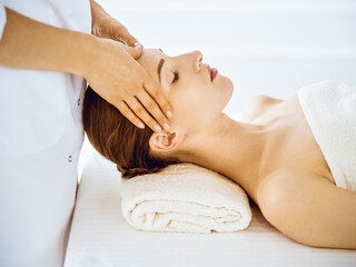 Obraz na płótnie Canvas Beautiful woman enjoying facial massage with closed eyes in spa center