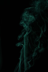green smoke from incense on a black background