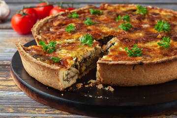 French quiche with chicken and mushrooms on wooden background
