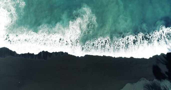 Top down aerial view from drone of nature volcanic black sand beach and beautiful waves.