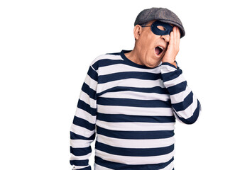 Senior handsome man wearing burglar mask and t-shirt yawning tired covering half face, eye and mouth with hand. face hurts in pain.