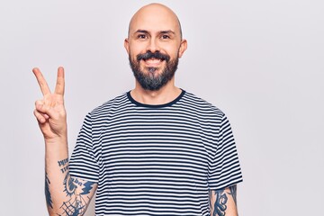 Young handsome man wearing casual clothes smiling with happy face winking at the camera doing victory sign. number two.