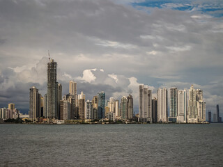 Obraz premium Panama City, Panama - November 30, 2008: Modern highrise building along gray bay water shoreline seen from historic downtown under blue cloudscape.