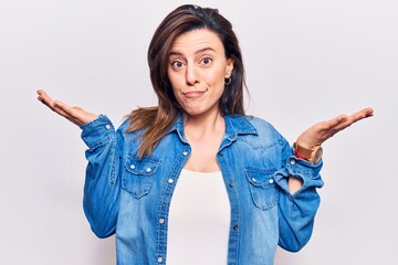 Young beautiful woman wearing casual clothes clueless and confused with open arms, no idea and...