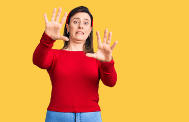 Young beautiful woman wearing casual clothes afraid and terrified with fear expression stop gesture with hands, shouting in shock. panic concept.