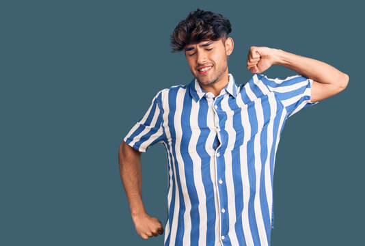 Young hispanic man wearing casual clothes stretching back, tired and relaxed, sleepy and yawning for early morning